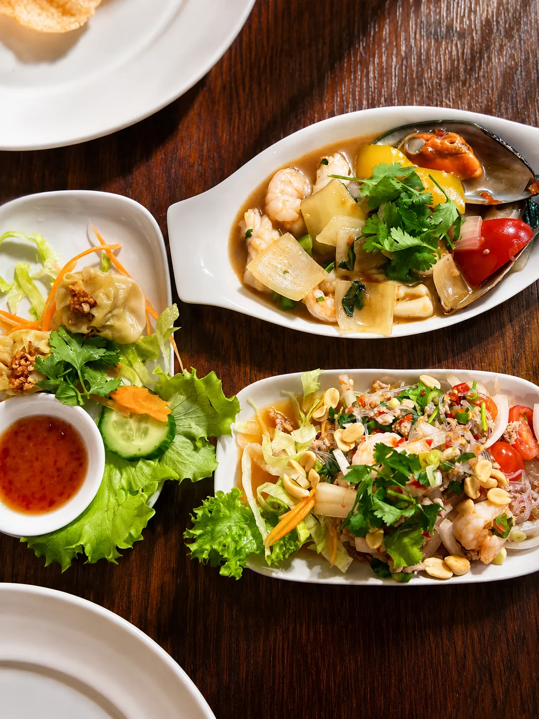 Seafood dishes and salad arranged on a dark wooden table
